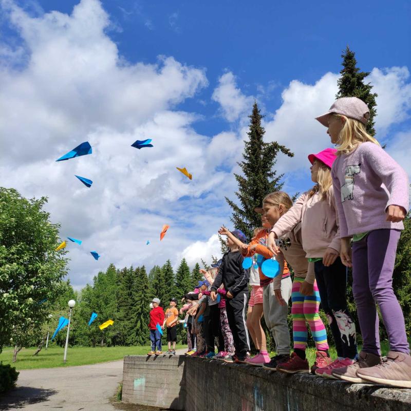 Lapsia heittämässä lennokkeja ilmaan.